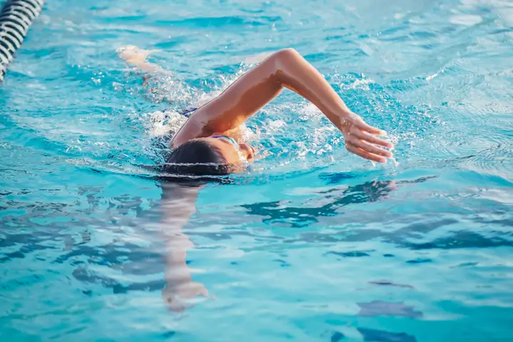A swimmer mid-stroke doing freestyle down a lane