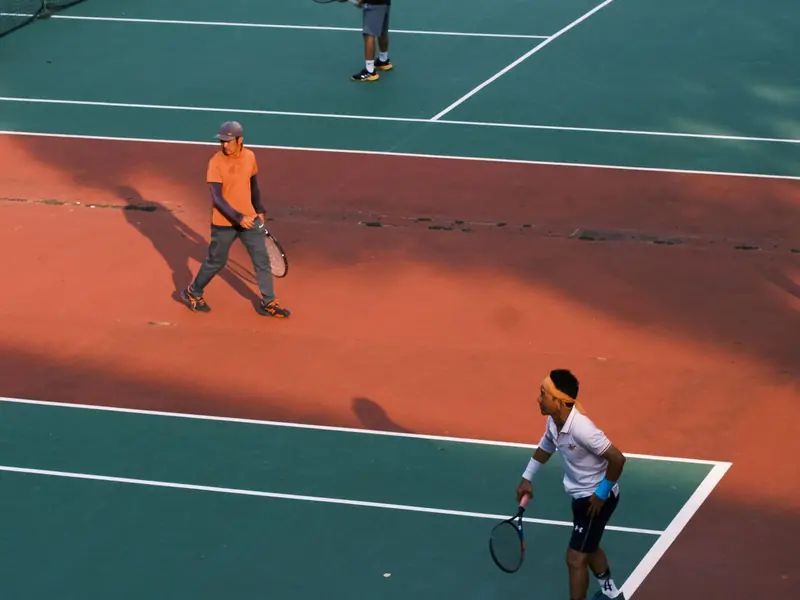 Three adults playing across neighbouring outdoor courts
