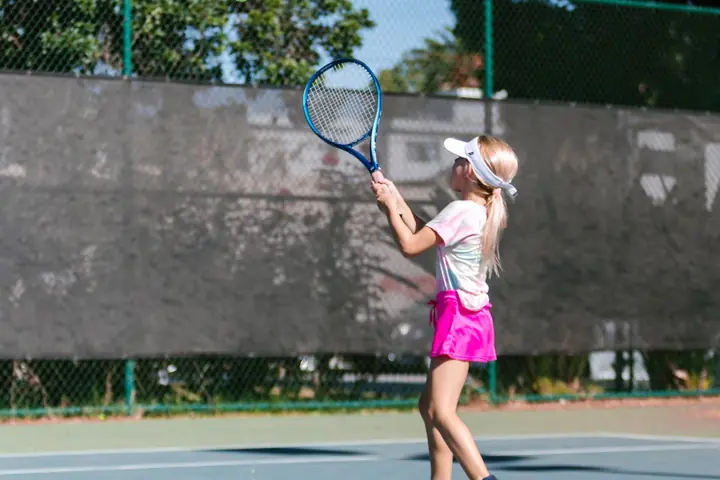 A young player from a distance, hitting a forehand on an outdoor court