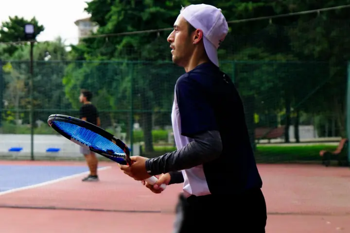 A young player with a racket, ready on an outdoor court